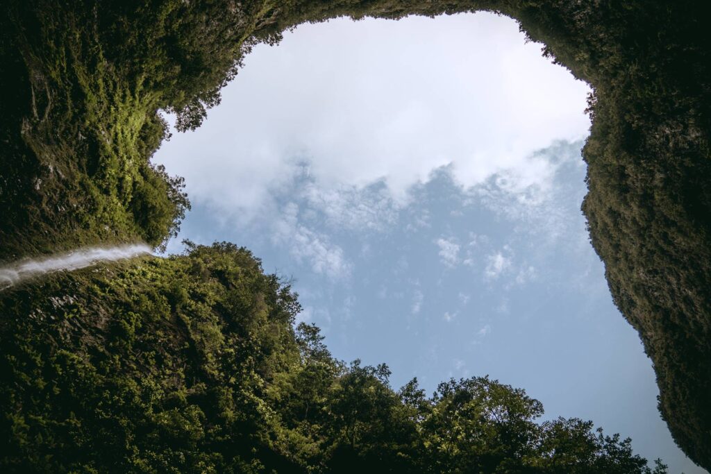 Au pied de la cascade, lorsqu'on lève les yeux, la montagne n'offre qu'une petite ouverture vers le ciel, créant un cirque de verdure.